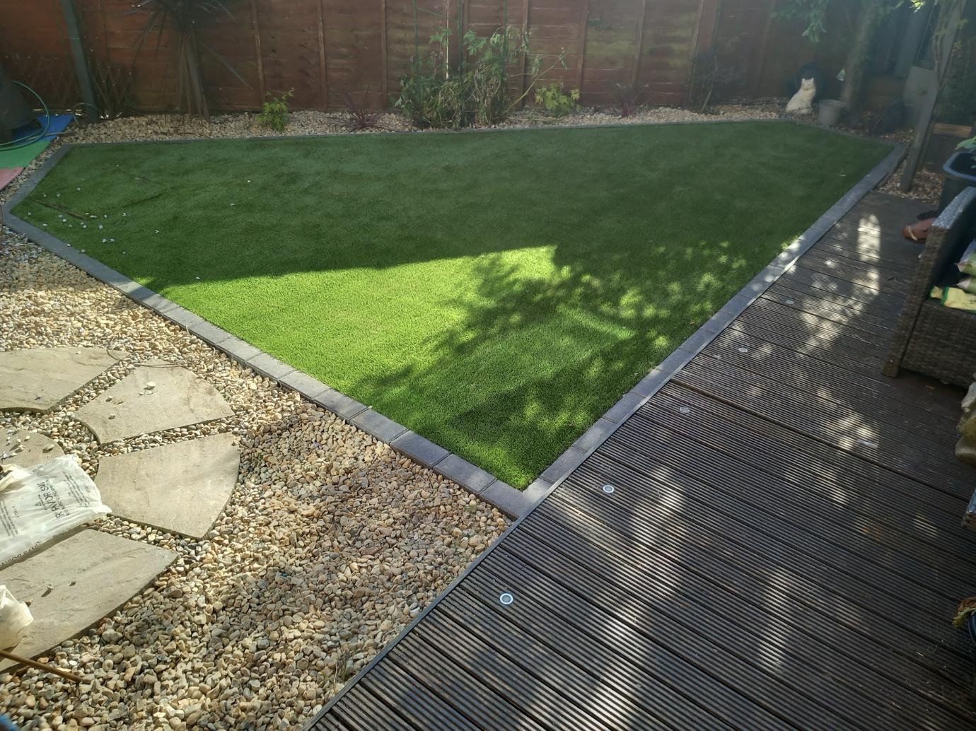 All year green artificial lawn with composite deck border and gravel edging by Lawn Ranger Landscapes