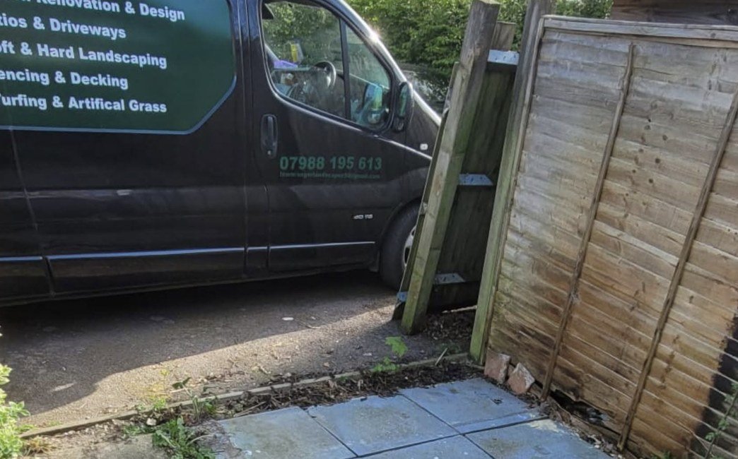 Broken leaning fence panel by the Lawn Ranger van before replacement