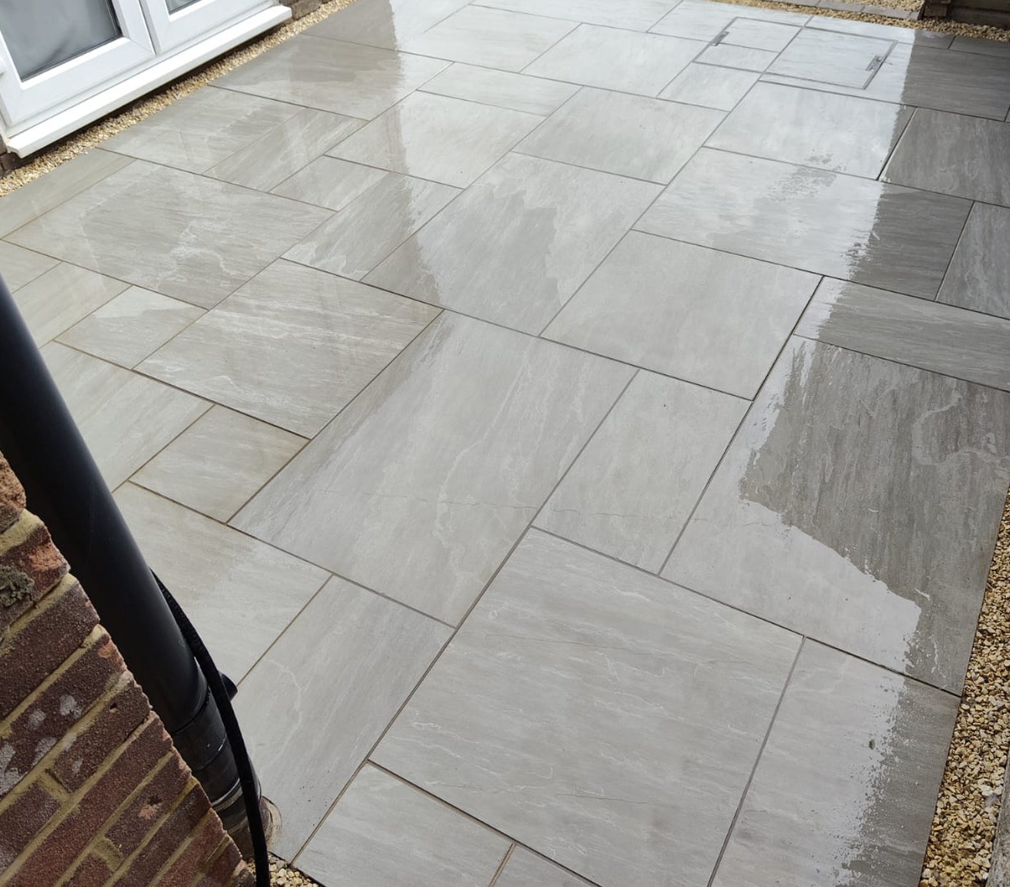 Close up of new Kandla Grey porcelain patio slabs with recessed drain covers by Lawn Ranger Landscapes, Lydd
