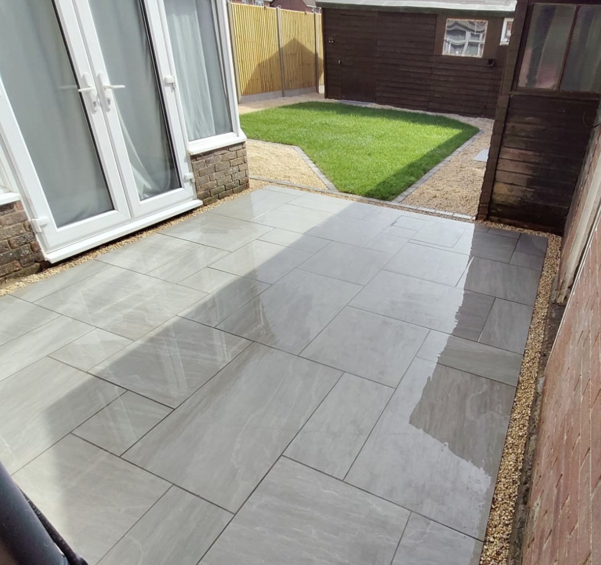 New Kandla Grey porcelain patio leading onto a fresh turf lawn with Yorkshire Cream shingle borders after a garden transformation in Lydd, Kent